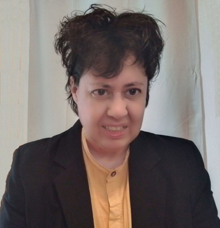 A woman wearing an orange shirt and black blazer.